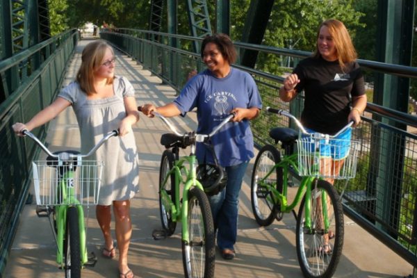 Women walk bikes across a bridge